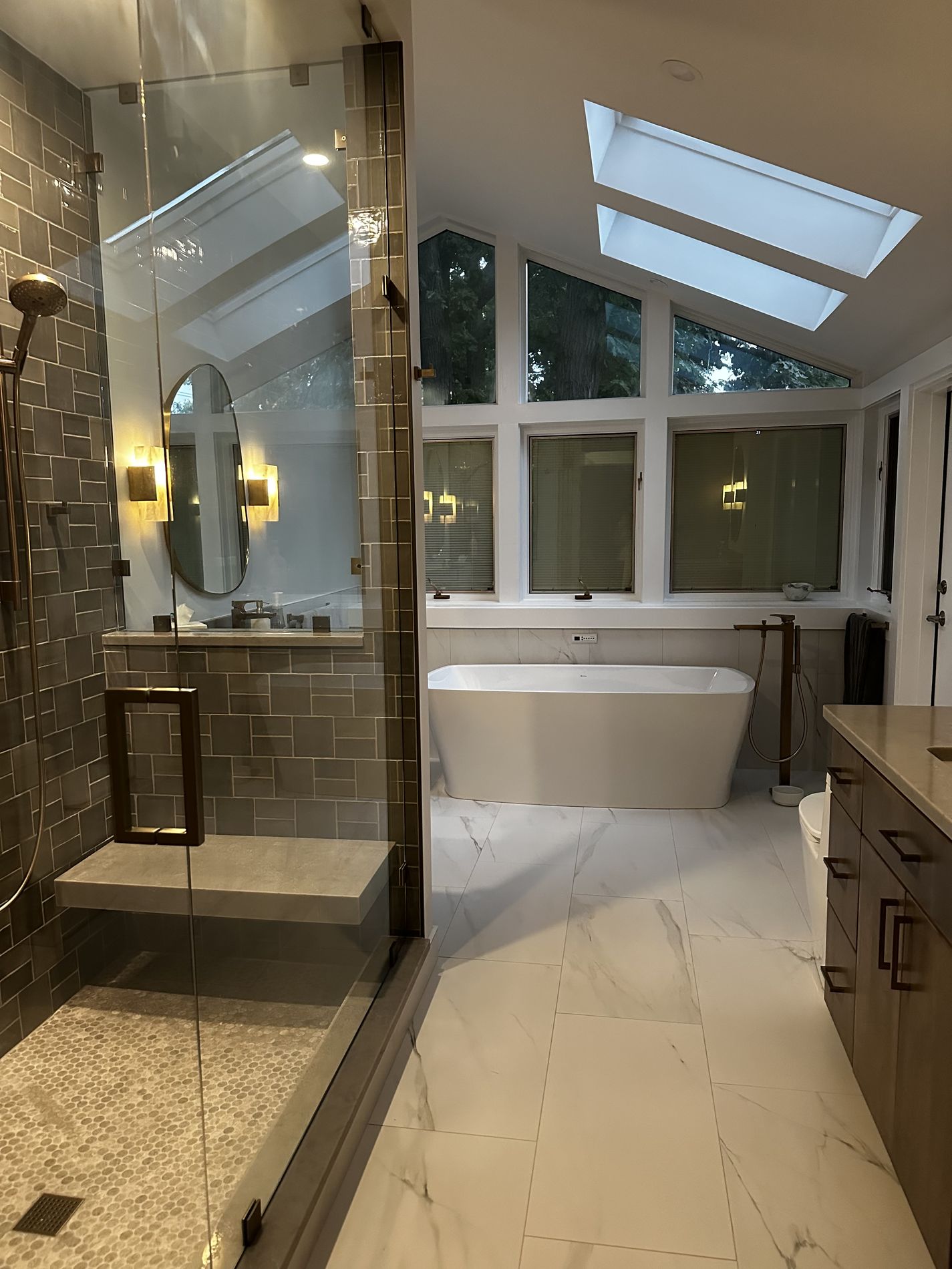 Vaulted primary spa bath with freestanding tub, glass shower and marble floors by Exclusive Home Build